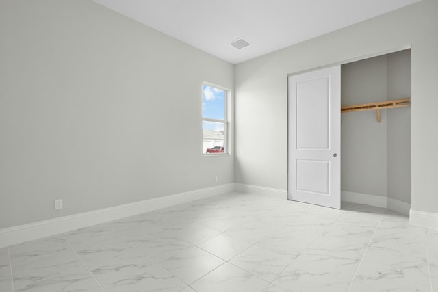 unfurnished bedroom with marble finish floor, visible vents, baseboards, and a closet