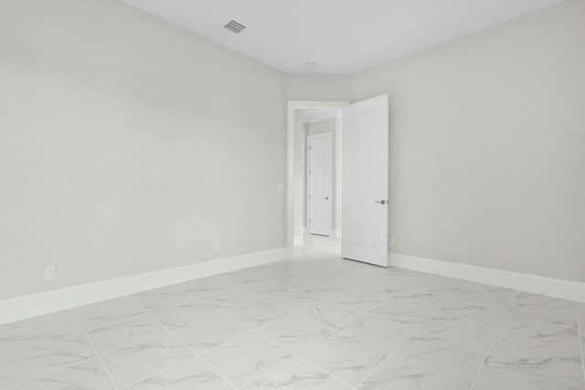 spare room with marble finish floor, visible vents, and baseboards