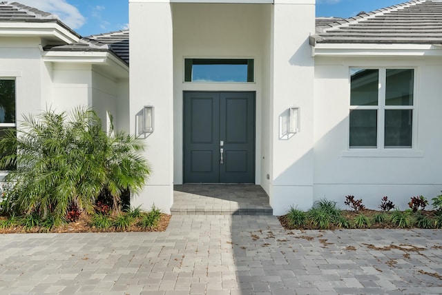 entrance to property featuring a tile roof and stucco siding