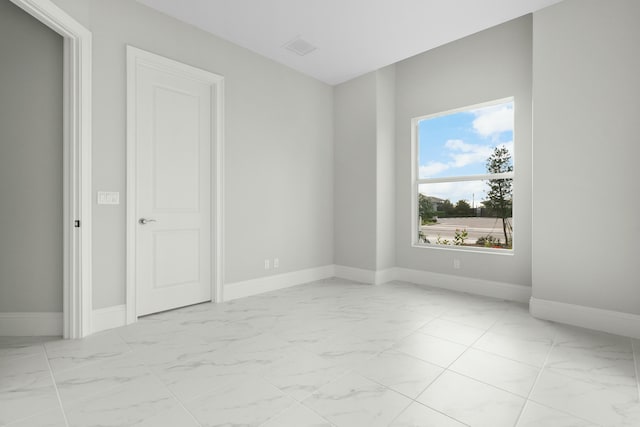 spare room featuring marble finish floor and baseboards