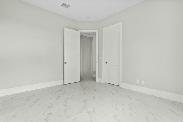 unfurnished room with marble finish floor, visible vents, and baseboards