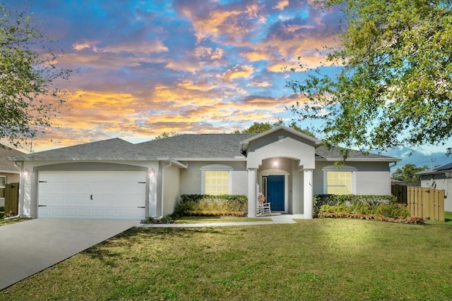 ranch-style home with a garage, concrete driveway, a front yard, and stucco siding