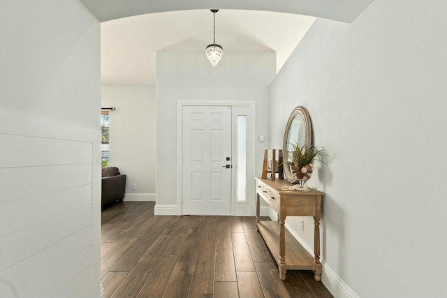 entryway with dark wood finished floors, arched walkways, baseboards, and vaulted ceiling