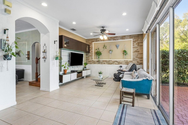 living area featuring light tile patterned floors, ceiling fan, arched walkways, recessed lighting, and crown molding