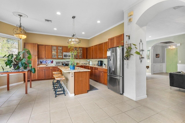 kitchen featuring visible vents, arched walkways, brown cabinets, stainless steel appliances, and crown molding