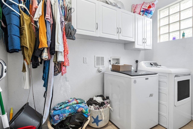 washroom featuring visible vents, washer and clothes dryer, and cabinet space