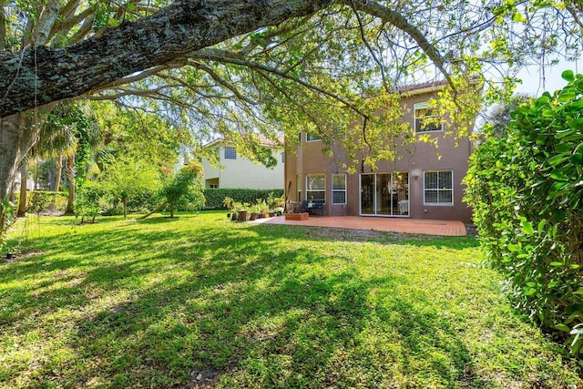 rear view of house with a yard, a patio, and stucco siding