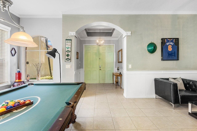 rec room featuring arched walkways, wainscoting, crown molding, and light tile patterned floors