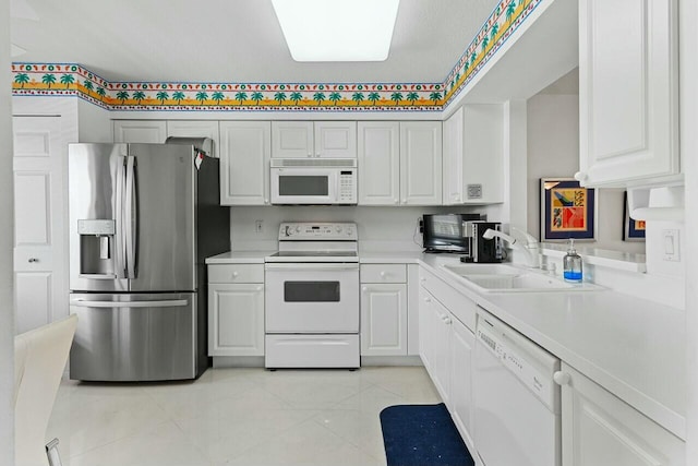 kitchen with white appliances, white cabinets, light countertops, a sink, and light tile patterned flooring