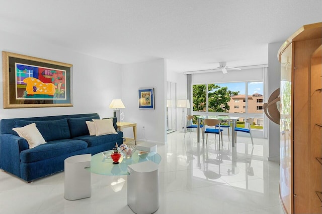 living room featuring ceiling fan, tile patterned floors, and baseboards