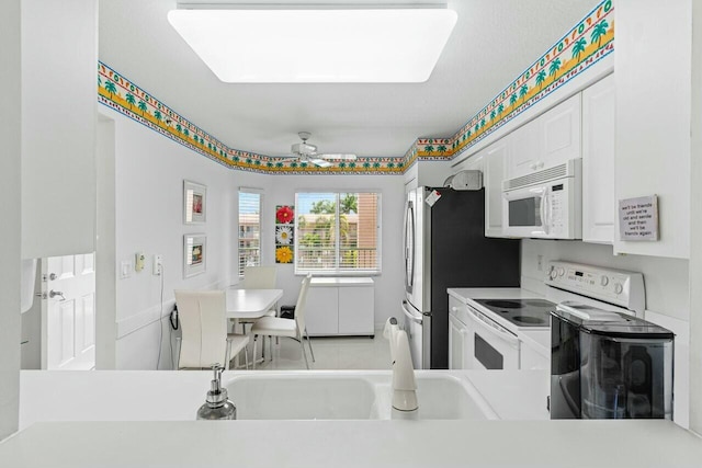 kitchen featuring ceiling fan, light countertops, white appliances, and white cabinets