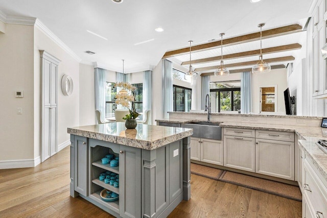 kitchen with light stone countertops, gray cabinets, a sink, and wood finished floors