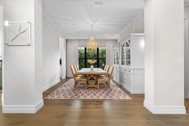 dining area with ornamental molding, a chandelier, baseboards, and wood finished floors