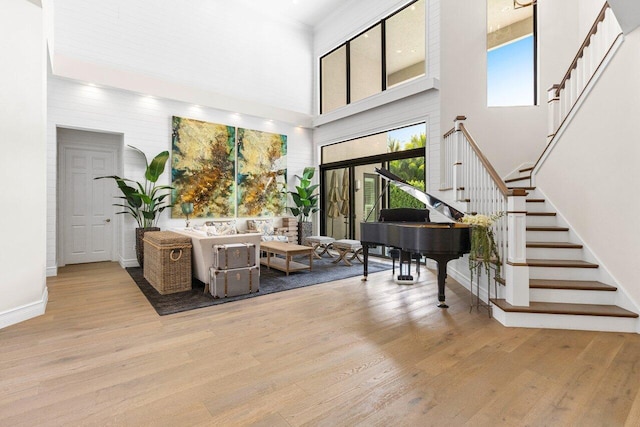 interior space featuring crown molding, a towering ceiling, wood finished floors, baseboards, and stairs