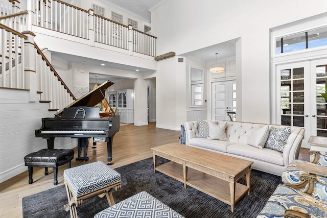 living room featuring french doors, a towering ceiling, wood finished floors, baseboards, and stairs