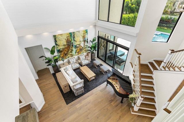 living room featuring stairs, baseboards, a high ceiling, and wood finished floors