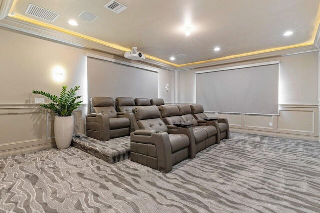 carpeted cinema featuring crown molding, wainscoting, visible vents, and a decorative wall