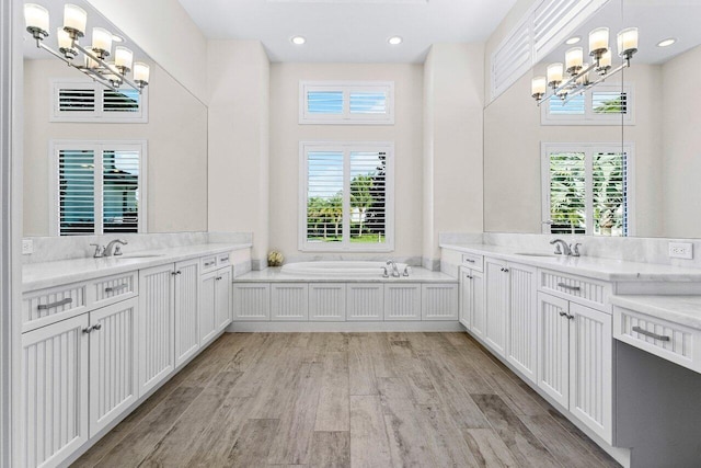 bathroom featuring a healthy amount of sunlight, an inviting chandelier, and wood finished floors