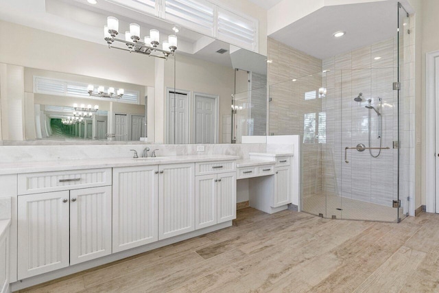 bathroom with visible vents, wood finished floors, an inviting chandelier, vanity, and a shower stall