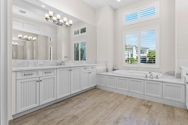 full bath featuring visible vents, wood finished floors, an inviting chandelier, vanity, and a bath