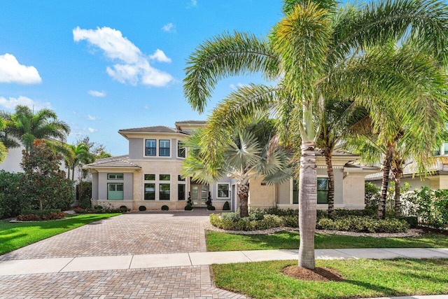 view of front facade with a front lawn, decorative driveway, and stucco siding