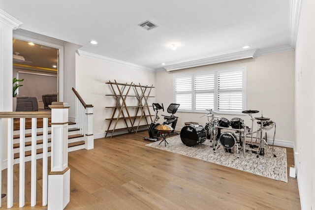 interior space with baseboards, visible vents, wood finished floors, and ornamental molding