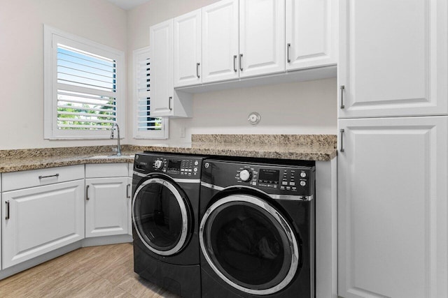 washroom featuring cabinet space, independent washer and dryer, and a sink