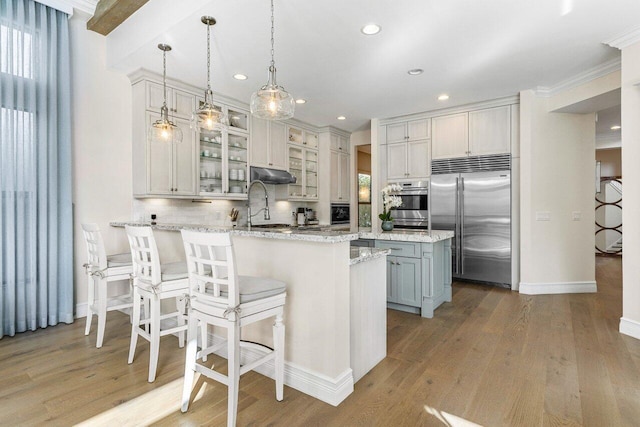 kitchen featuring a peninsula, appliances with stainless steel finishes, wood finished floors, and under cabinet range hood