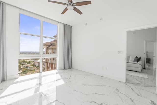 unfurnished room featuring a wall of windows, marble finish floor, baseboards, and a ceiling fan