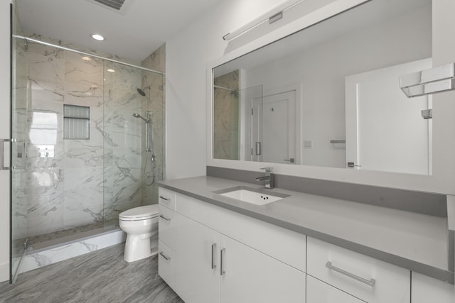 bathroom with a marble finish shower, marble finish floor, toilet, and vanity