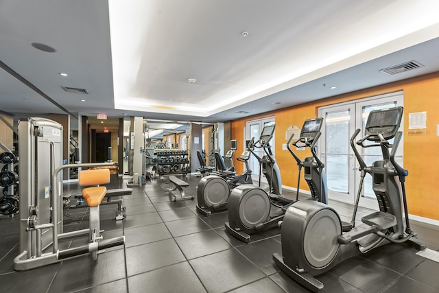 workout area featuring a tray ceiling, visible vents, and baseboards