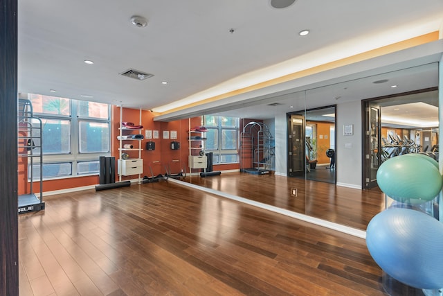 exercise room with recessed lighting, wood finished floors, visible vents, and baseboards