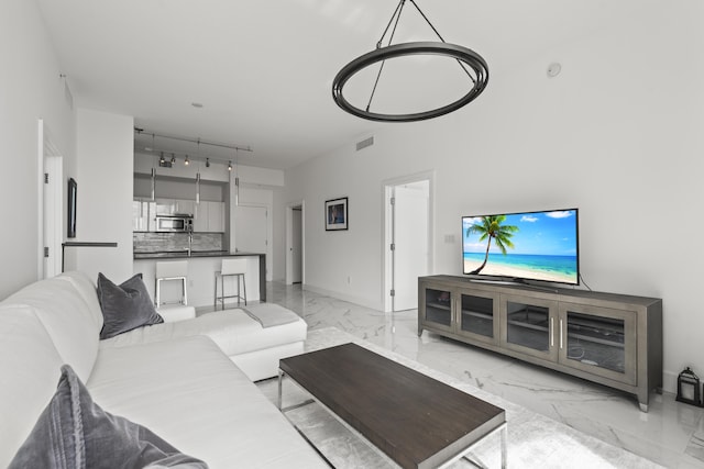 living area featuring marble finish floor, baseboards, visible vents, and track lighting