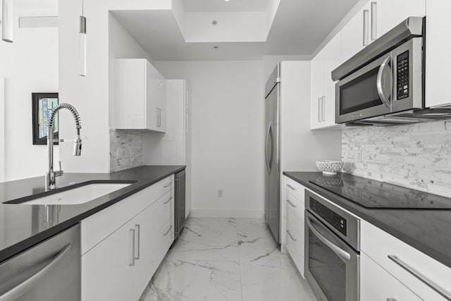 kitchen with baseboards, white cabinets, marble finish floor, stainless steel appliances, and a sink