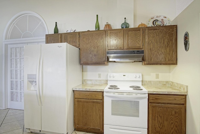 kitchen featuring brown cabinets, light tile patterned floors, light countertops, white appliances, and under cabinet range hood