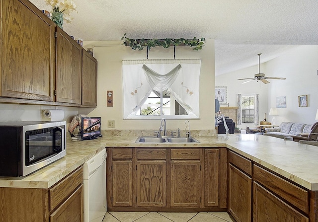 kitchen featuring white dishwasher, a peninsula, a sink, light countertops, and stainless steel microwave