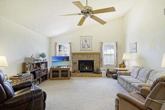 living area with a textured ceiling, vaulted ceiling, a tile fireplace, and carpet flooring