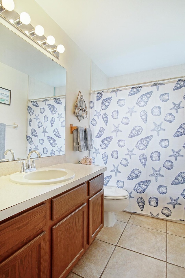 bathroom with a shower with curtain, vanity, toilet, and tile patterned floors