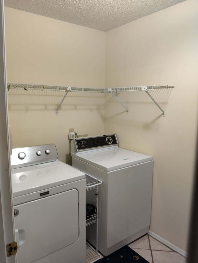 laundry room featuring washing machine and dryer, laundry area, light tile patterned flooring, and a textured ceiling