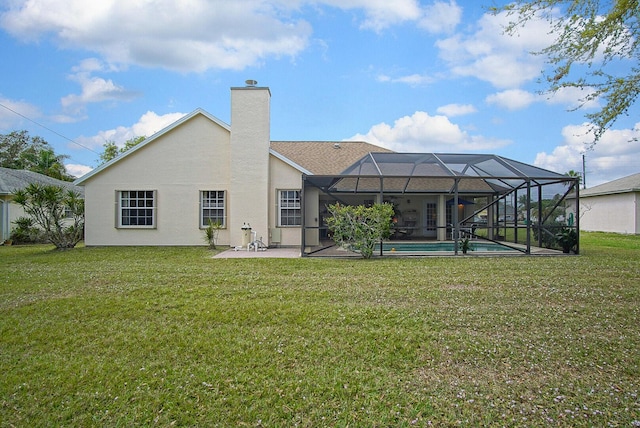 rear view of house with a chimney, stucco siding, a lawn, a patio area, and a lanai