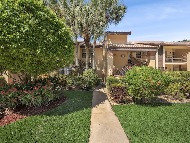 exterior space featuring a front yard, a tile roof, and stucco siding