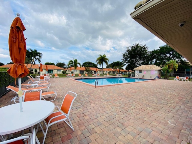 community pool with a patio and fence