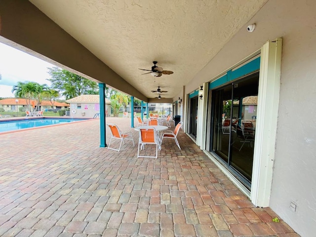 view of patio with a community pool, a ceiling fan, and outdoor dining space