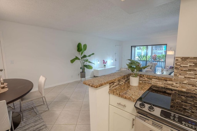 9785 Pineapple Tree Dr Unit 103, Boynton Beach, FL 33436 - kitchen featuring stove, tasteful backsplash, light stone counters, light tile patterned flooring, and a textured ceiling