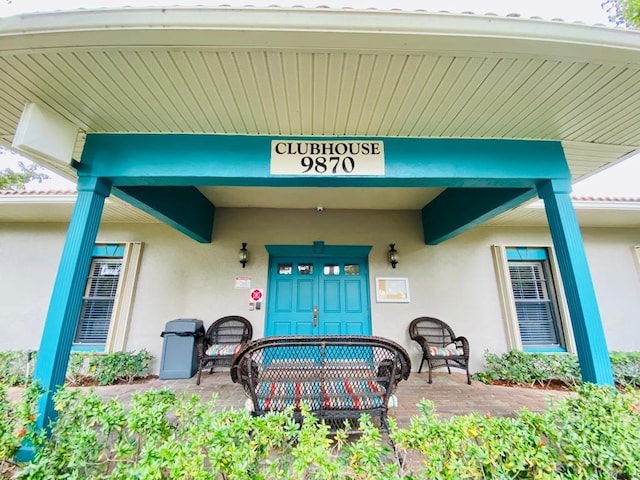 entrance to property with covered porch and stucco siding