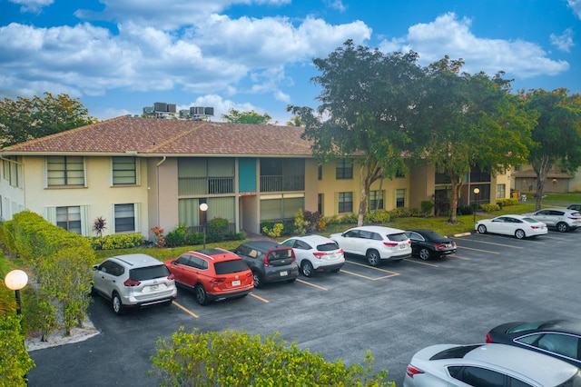view of building exterior with central air condition unit and uncovered parking