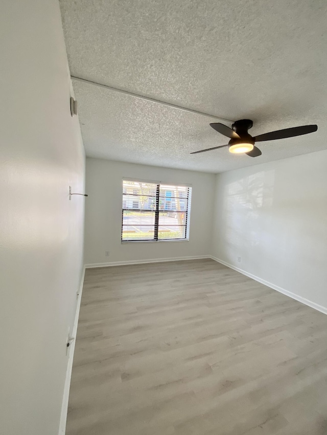 unfurnished room with light wood-style floors, baseboards, a ceiling fan, and a textured ceiling