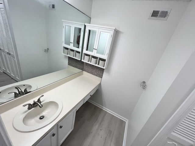 bathroom with baseboards, visible vents, wood finished floors, and vanity
