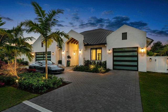 modern home with a gate, decorative driveway, metal roof, and a standing seam roof