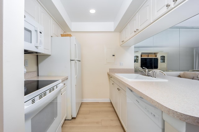 kitchen with white appliances, white cabinetry, light wood finished floors, and a sink